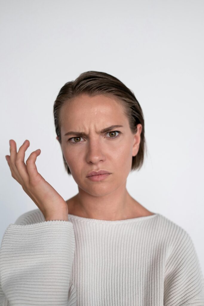 A confused young woman with a questioning facial expression on a white background.