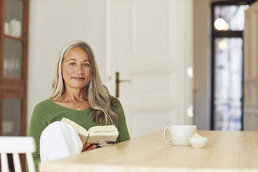 woman-with-book-sitting-by-table-at-home-MCF01065